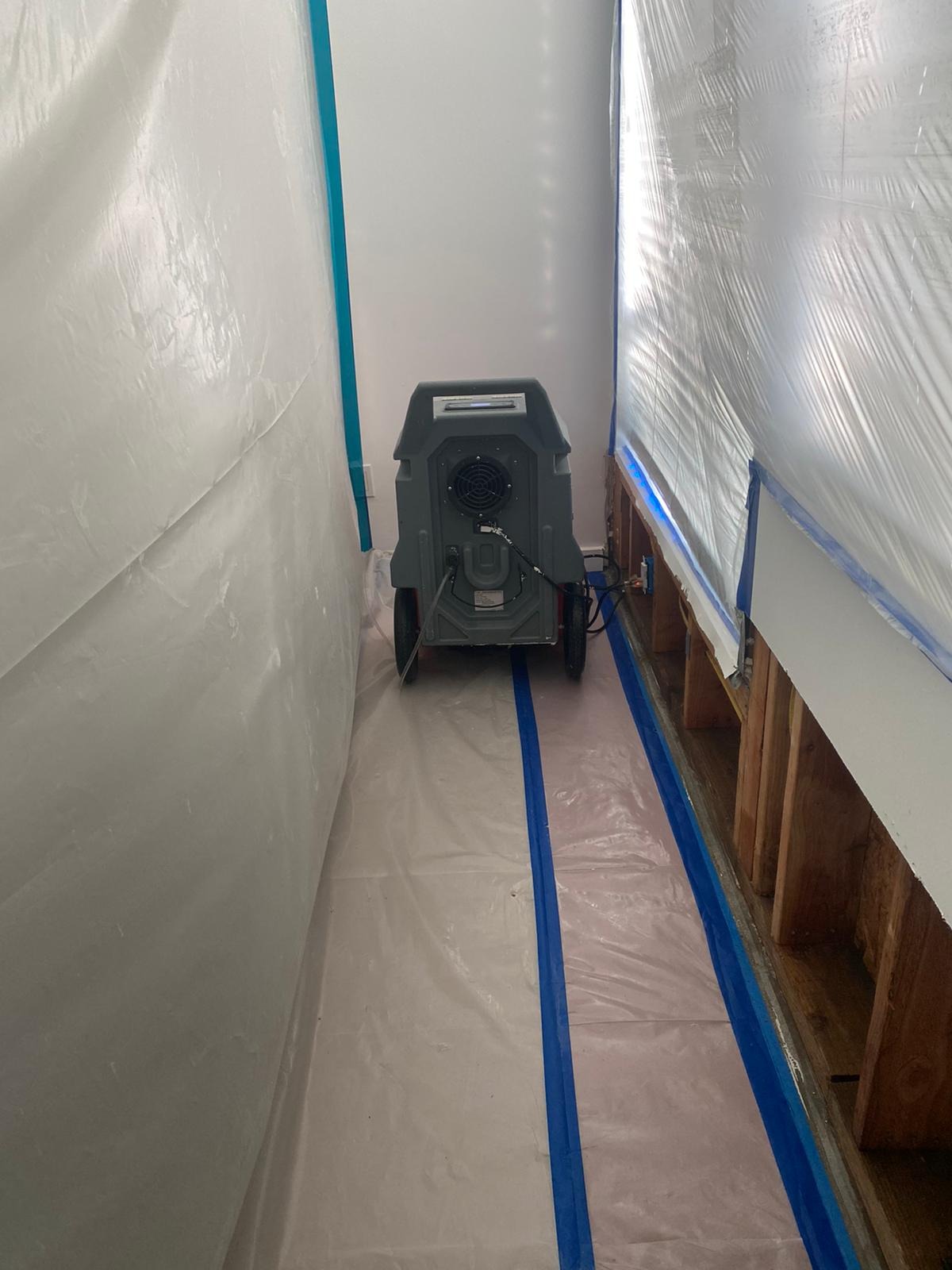 Water mitigation equipment beside an opened lower wall cavity in Central Los Angeles