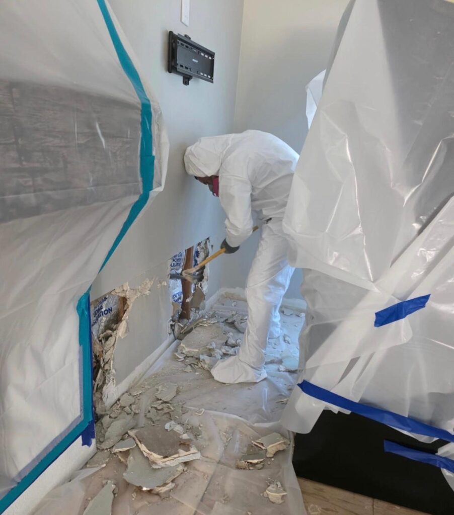 Technician removing affected wall materials inside containment during a Long Beach, CA 90808 water damage project.