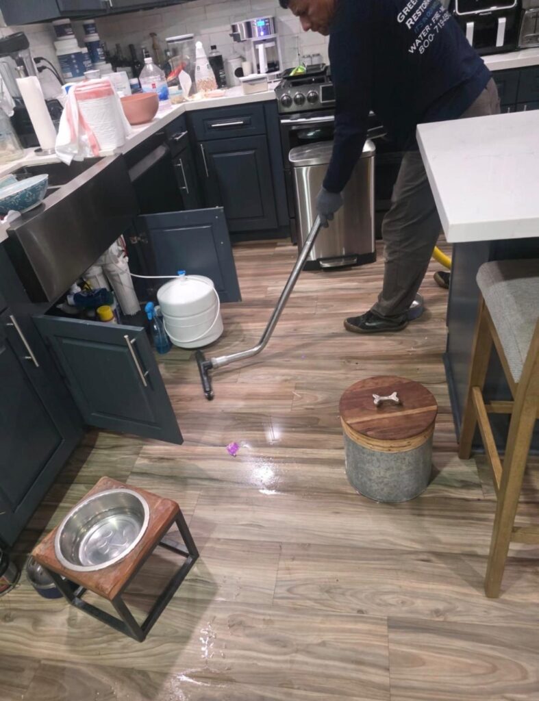 Green Planet Restoration technician extracting water from kitchen flooring in Long Beach, CA 90808.