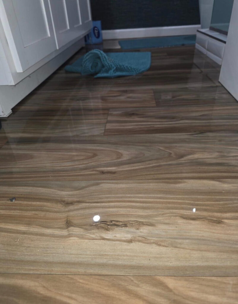 Water on flooring near a bathroom area during a Long Beach, CA 90808 water damage project.