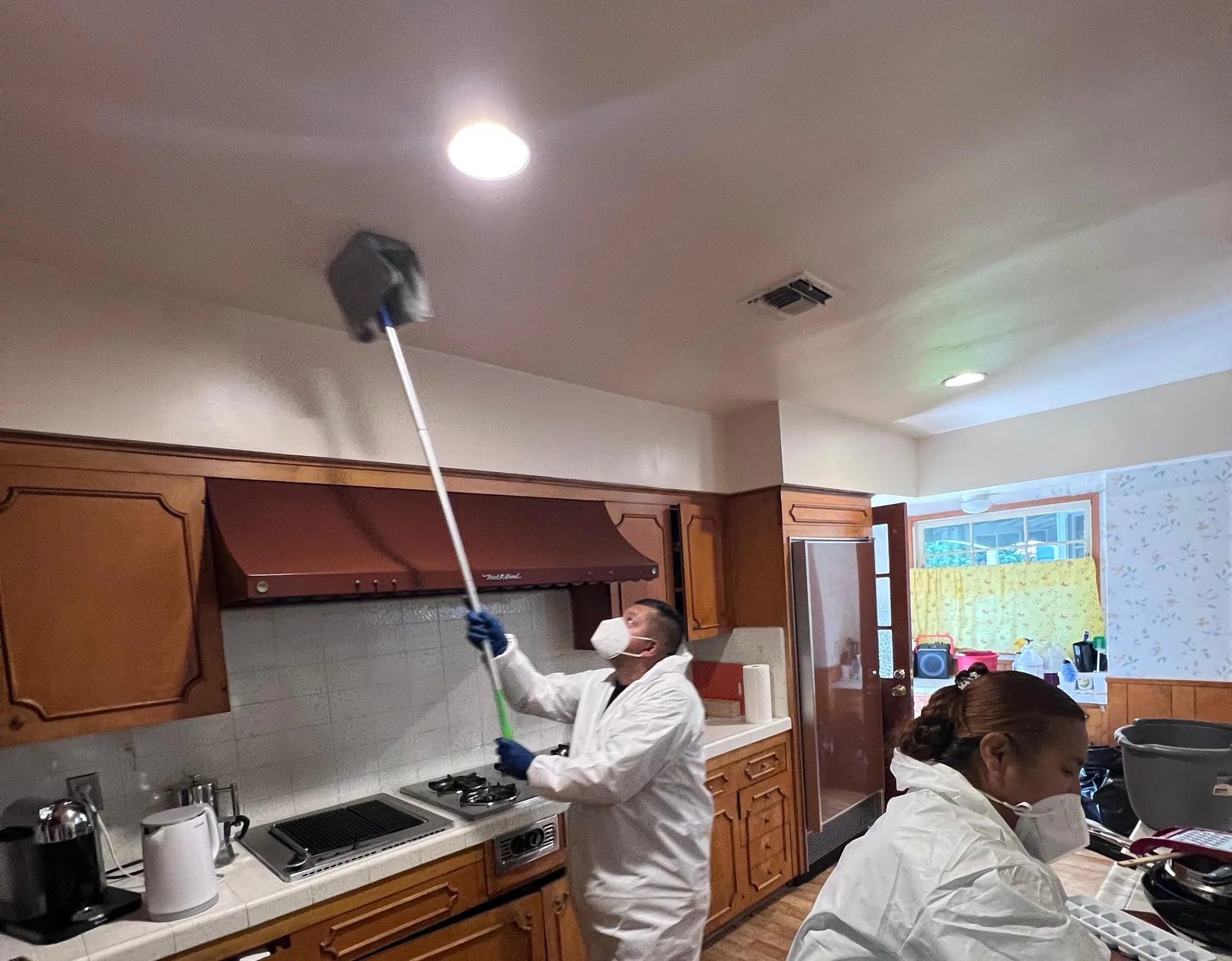 Technician cleaning soot from a kitchen ceiling