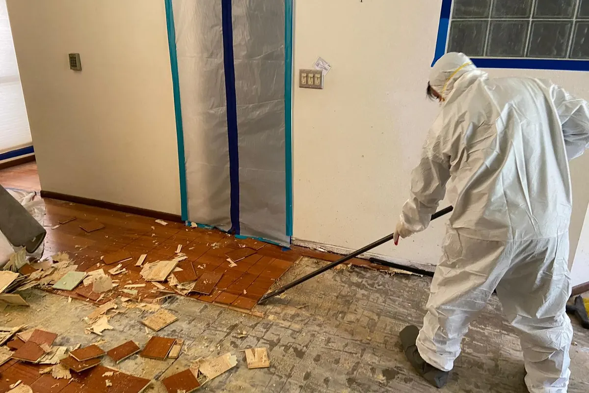Technician in a protective suit clearing damaged material