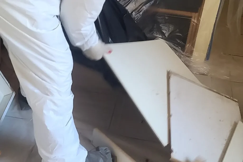 Technician in protective gear removing moldy material