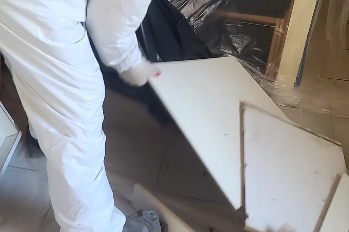 Technician in protective gear removing moldy material