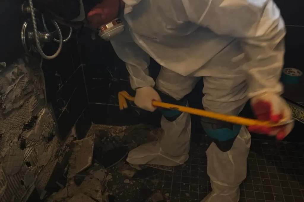 Technician in full protective gear removing contaminated materials